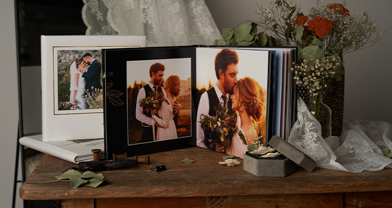An elegant wedding photo album with beautiful wedding photos of the bride and groom, set on a rustic table next to flowers and a keepsake box - the perfect way to share your wedding photos and preserve your memories.