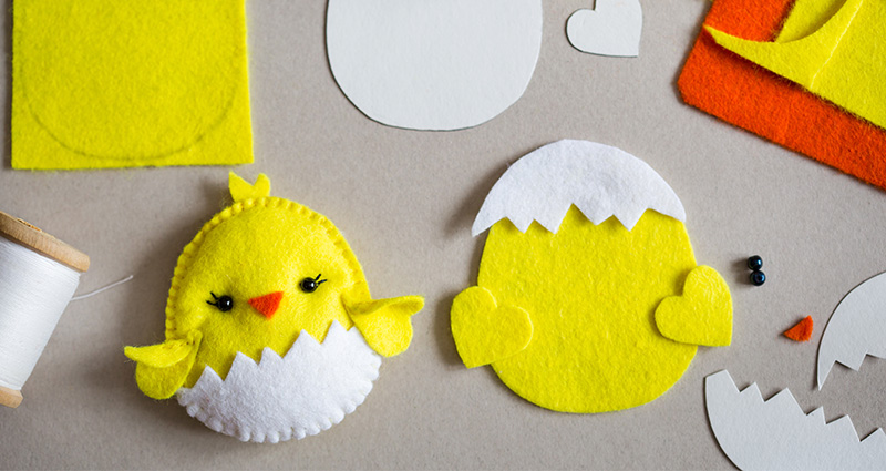 Easter chicken made of felt. Near that threads, paper templates and colourful sheets of felt.