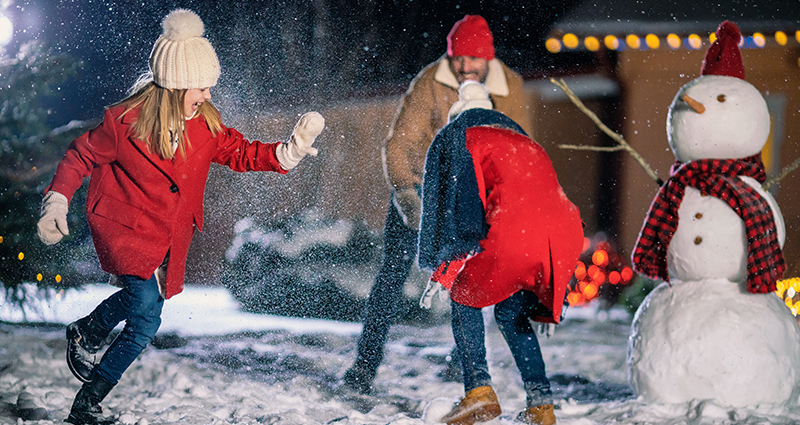 Two girls throwing snowballs on a winter evening