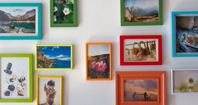 Close-up on photos in coloured frames hung on a wall.