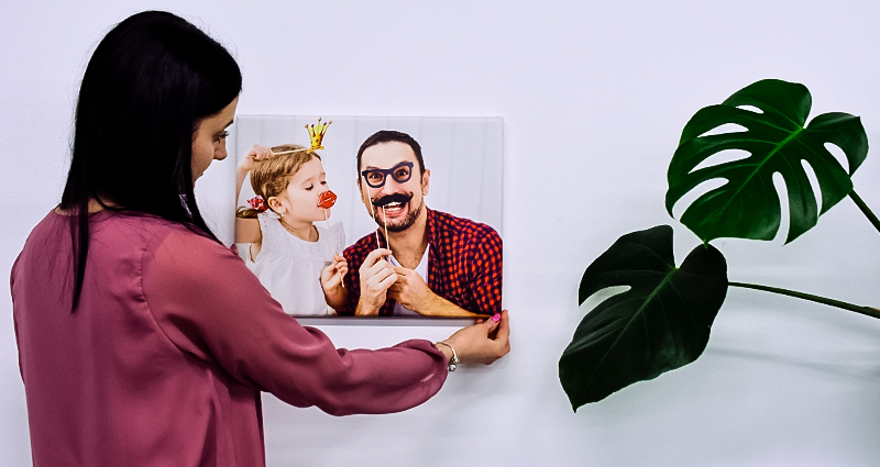 Mujer colgando un lienzo que presenta a un padre y su niña.