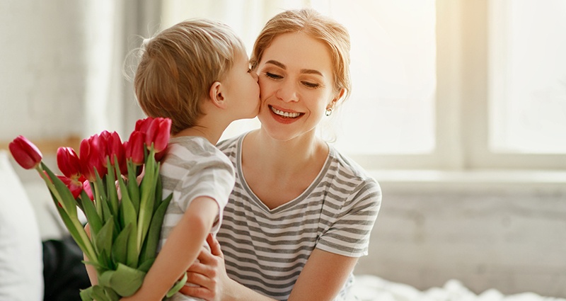 Le fils qui donne des fleurs à sa maman en lui souhaitant que du bonheur à l'occasion de fêtes des mères