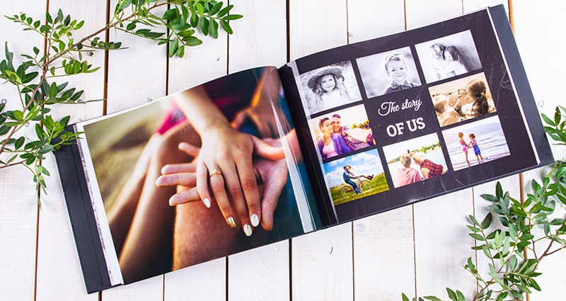 Le zoom sur un livre photo ouvert et une photo des mains de couple d'amoureux (une bague de fiançailles sur le doigt annulaire de femme) sur la page à côté il y a un collage des photos.