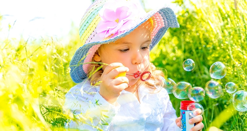 Un enfant  faisant bulles de savon sur un pré.