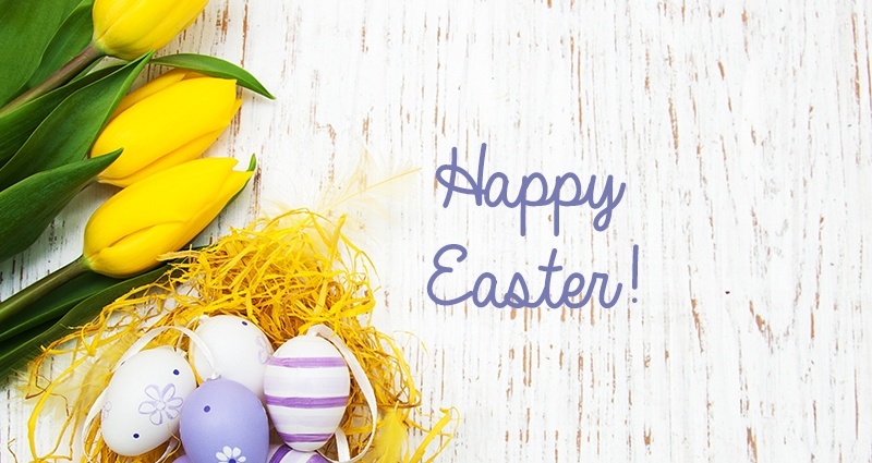 Violet-white Easter Eggs in a yellow raffia nest. Next to it yellow tulips against a bright backdrop. The "Happy Easter!" caption in the middle of the photo.