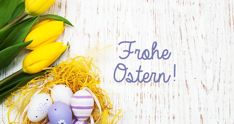 Violett-weiße Ostereier in einem gelben Nest aus Raffia. Daneben gelbe Tulpen auf wei-em Hintergrund. In der Mitte der Text: "Frohe Ostern!".